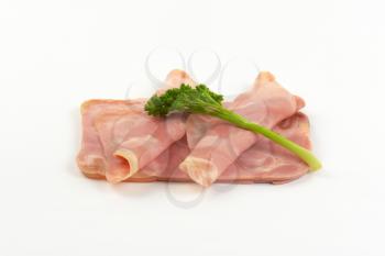 slices of pork ham with parsley on white background