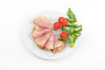 plate of ham slices with fresh dill and cherry tomatoes on white background