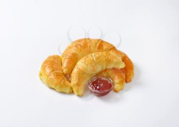 jam filled croissants and bowl of strawberry jam on white background