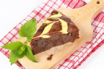 slice of chocolate cake with cream cheese on wooden cutting board - close up