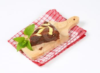 slice of chocolate cake with cream cheese on wooden cutting board