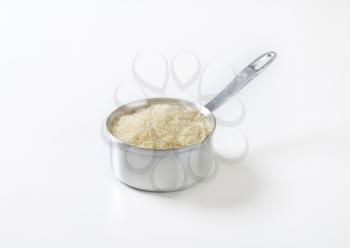 saucepan of uncooked rice on white background