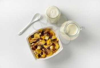 bowl of mixed breakfast cereals, jug of milk and jar of yogurt
