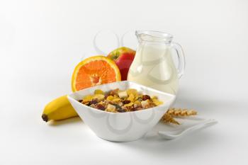 bowl of mixed breakfast cereals, jug of milk and fresh fruit
