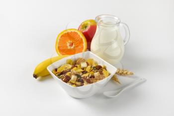 bowl of mixed breakfast cereals, jug of milk and fresh fruit