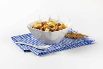 bowl of mixed breakfast cereals with dried fruit on blue checkered dishtowel