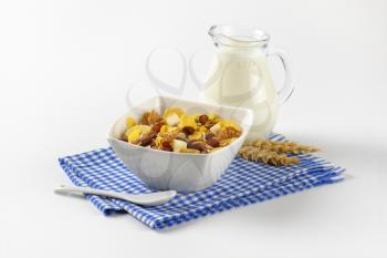 bowl of mixed breakfast cereals and jug of milk on blue checkered dishtowel