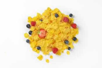 pile of corn flakes with berry fruits on white background