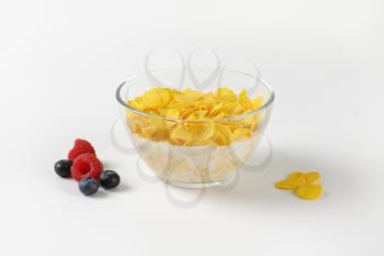 bowl of corn flakes with fresh milk on off-white background with shadows