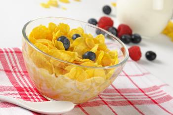 bowl of corn flakes with fresh milk on checkered dishtowel - close up