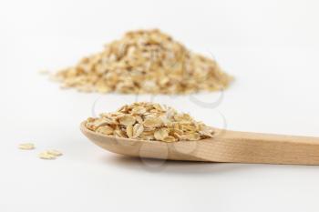 spoon of oat flakes on white background - close up