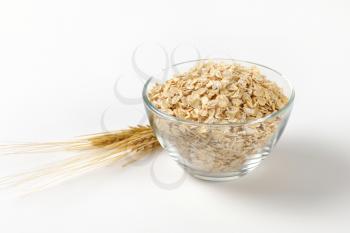 bowl of oat flakes on off-white background with shadows