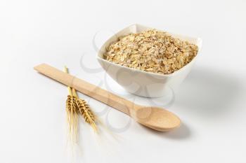 bowl of oat flakes on off-white background with shadows