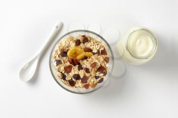 bowl of oat flakes and glass of white yogurt on off-white background with shadows