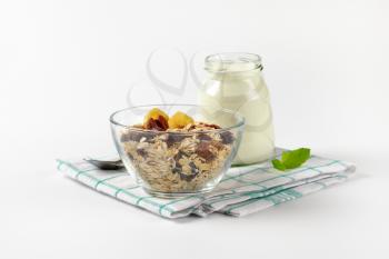 bowl of oat flakes and glass of white yogurt on checkered dishtowel