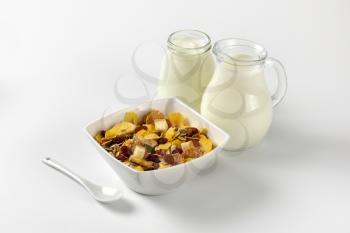 bowl of mixed breakfast cereals, jug of milk and jar of yogurt
