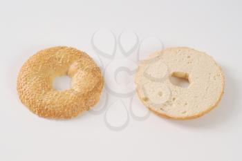 halved bagel with sesame seeds on white background