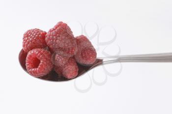 spoon of fresh raspberries on white background