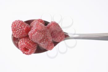 spoon of fresh raspberries on white background