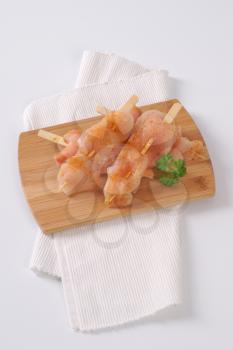 raw chicken skewers on wooden cutting board