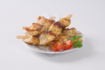 Chicken satay - grilled chicken skewers on white plate