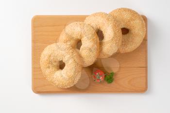 fresh bagels with sesame seeds on wooden cutting board