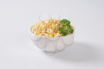 bowl of sweet corn kernels on off-white background with shadows