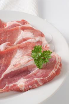 three slices of raw pork meat on white plate