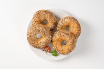 fresh bagels topped with seeds on white plate