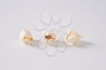 three pieces of fresh popcorn on white background