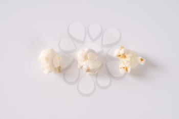 three pieces of fresh popcorn on white background