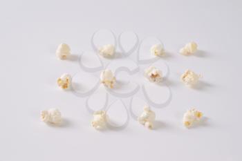 pieces of fresh popcorn arranged in rows on white background