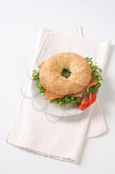 sesame bagel sandwich with smoked salmon on white plate