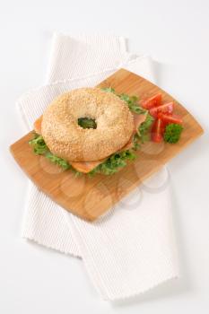 sesame bagel sandwich with smoked salmon on wooden cutting board
