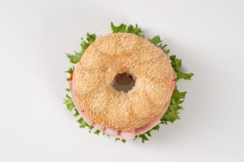sesame bagel sandwich with ham on white background