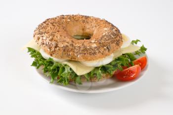 bagel sandwich with eggs and cheese on white plate
