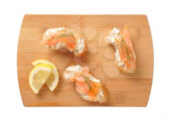 Bread based smoked salmon canapes on wooden cutting board