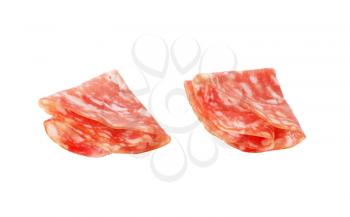 two folded slices of dry salami on white background