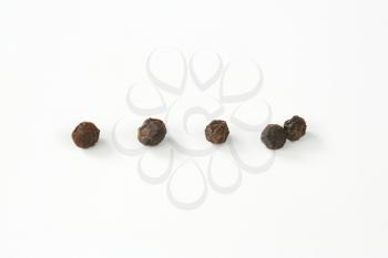 group of black peppercorns on white background