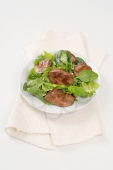 plate of pan fried liver with greens on white place mat