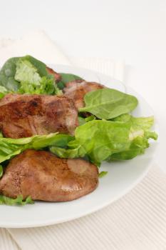 plate of pan fried liver with greens on white place mat