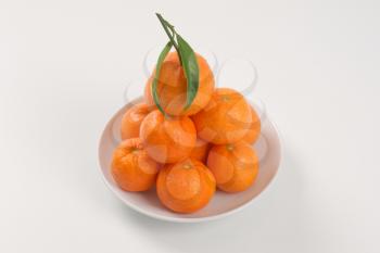 stack of fresh tangerines on white plate