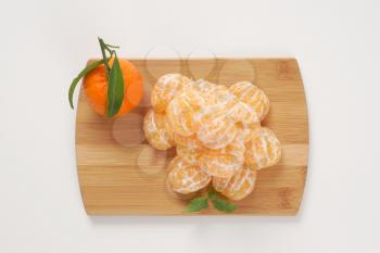 stack of peeled tangerines on wooden cutting board