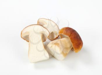whole and halved boletus mushrooms on white background