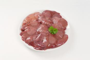 plate of raw chicken liver on white background