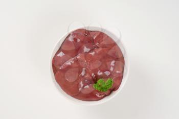 bowl of raw chicken liver on white background
