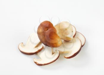 whole and sliced boletus mushrooms on white background