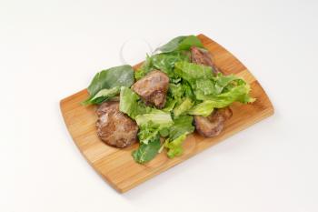pan fried liver with greens on wooden cutting board