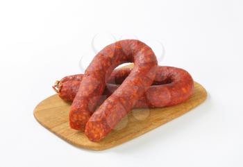 spicy sausages on wooden cutting board