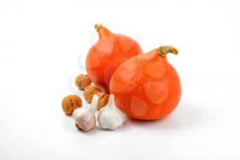 two orange pumpkins with garlic and walnuts on white background